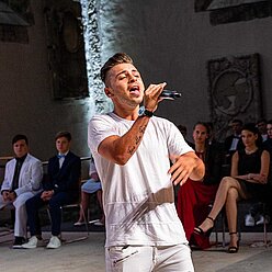 ein Mann, der in ein Mikrofon singt, während die Leute zusehen