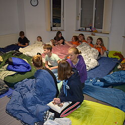 eine Gruppe von Kindern in einem Raum bei einer Übernachtung mit Schlafsäcken