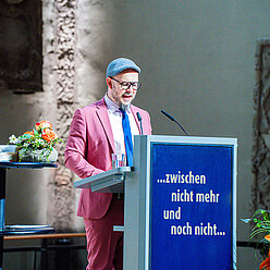 ein Mann in einem Anzug und Krawatte, der eine Rede hält
