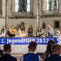 eine Gruppe von Menschen, die auf einer Bühne sitzen