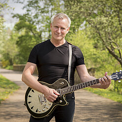 ein Mann, der eine Gitarre in der Hand hält