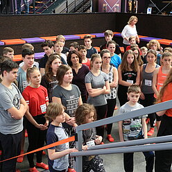 eine Gruppe von Menschen stehen in einem Raum vor einer Treppe